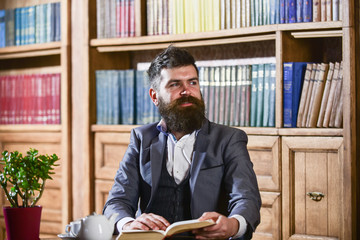 Aristocrat on smiling face holds book. Man in classic suit