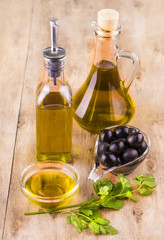 Olive oil with fresh herbs and Black olives  on wooden