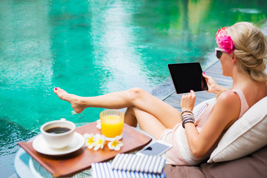 Girl with tablet by the pool