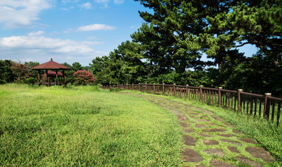 Fototapeta na wymiar Jeju olle pathway through a park with a little gardenhouse in Seogwipo, Jeju Island, South Korea