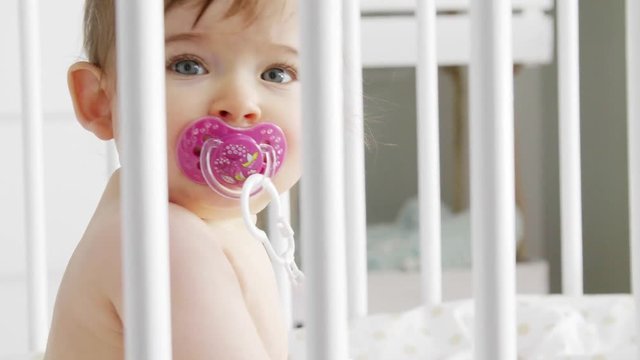 Cute baby girl sitting in crib 
