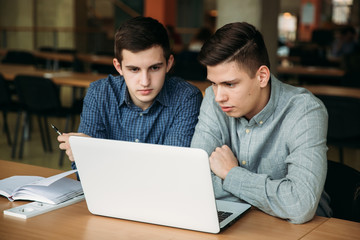 Two boy student use laptop in library