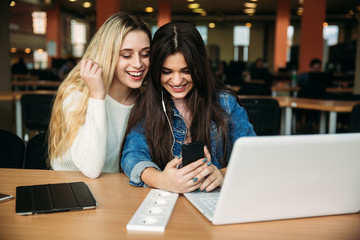 Two girl student use tablet and laptop in library