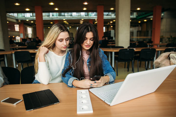 Two girl student use tablet and laptop in library. And listen music
