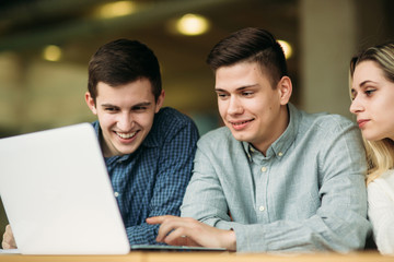 Group of college students studying in the school library, a girl and a boy are using a laptop and connecting to internet