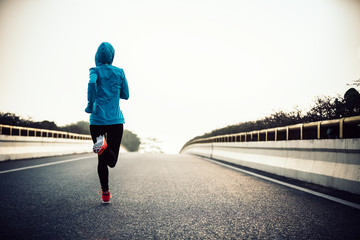 Young fitness woman runner running on road