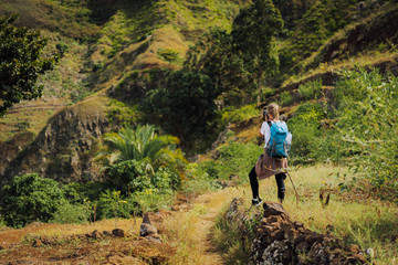 Fototapeta premium Woman tourist with blue backpack making photo of landscape in Mountains of Santo Antao island, Cabo Verde