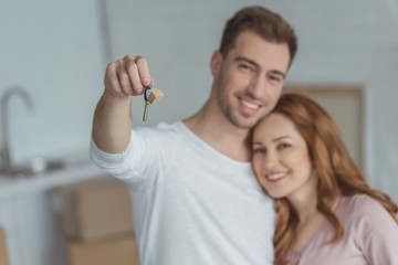 happy young couple holding key from new home and smiling at camera