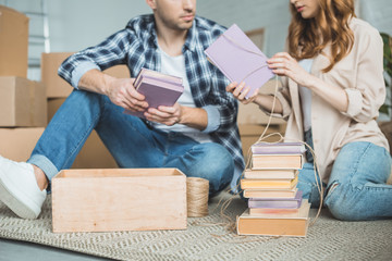 cropped shot of young couple packing books during relocation