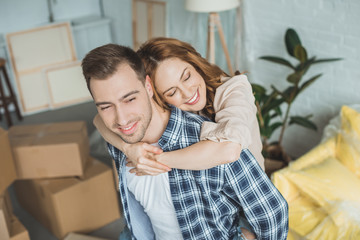 portrait of smiling wife hugging husband at new apartment, moving home concept