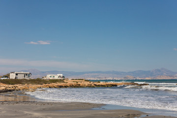Caravan motorhome parked on the beach in front of the blue sea in a beautiful place of wild nature