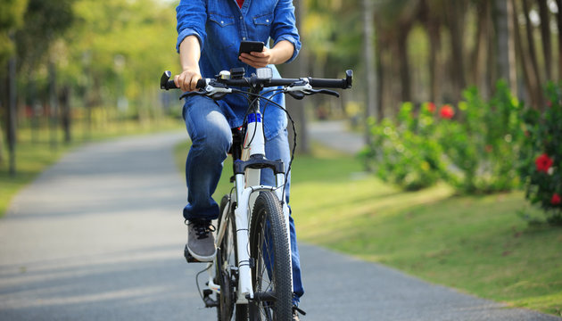 cyclist use cellphone while riding bike in tropical park