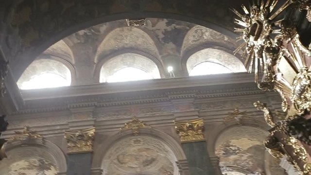 Overview of the beautiful gothic church decorated with golden sculptures. The sun is breaking through round windows on the roof. Historic architecture.