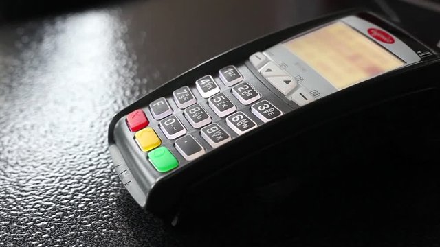 Man's hand swipe credit card payment on pos terminal. Closeup.