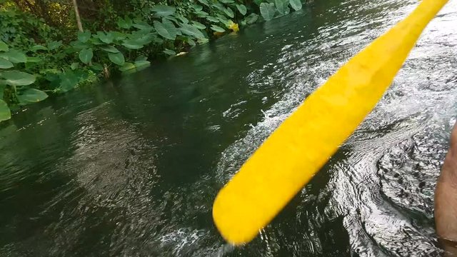 a man sits on a rubber boat and takes a rowing paddle down the river.
