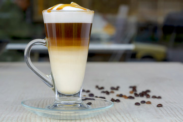 Glass of hot caramel macchiato coffee and coffe bean on table