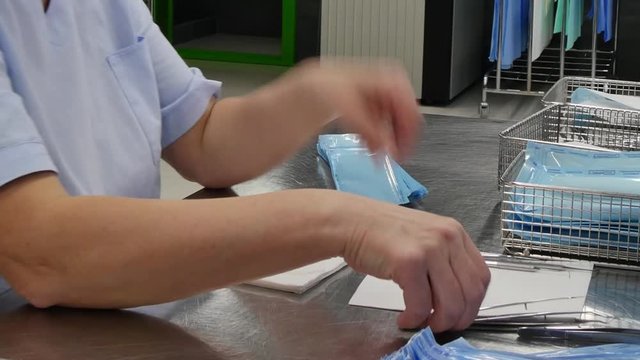 Women wraps in serviette and puts medical instruments in box. Set sterile tools. Professional work of surgeon doctor.