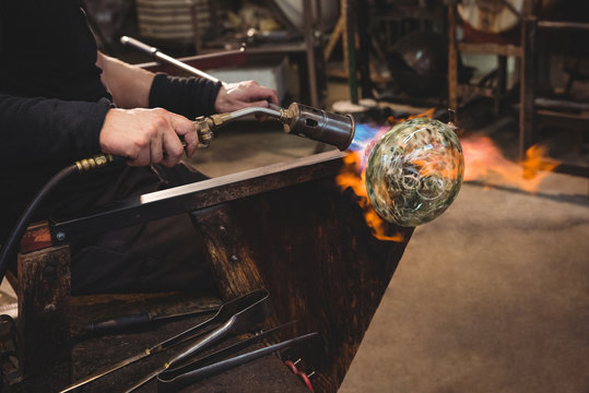 Glassblower giving final touch to a piece of glass with glassblowing torch