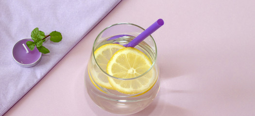 Glass of water and lemon. Glass of pure water and fresh organic lemon isolated on purple background. Detox and healthy food concept. Boost your metabolism concept