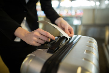 Airline check-in attendant sticking tag to the luggage of commuter 
