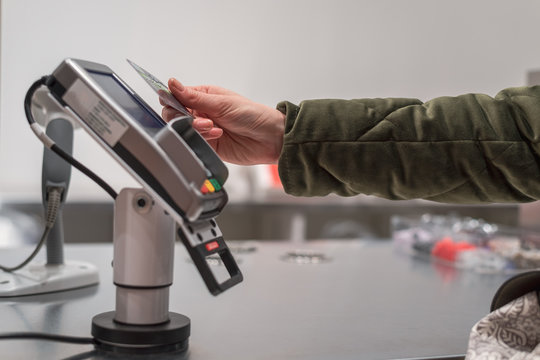 Women's hand pays for purchases in the store card contactless way, wireless technology, paypass