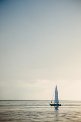Obraz premium Sailing boat on open sea at sunset.
