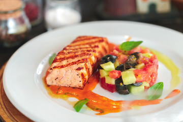 plate of grilled salmon steak with vegetables on wooden table