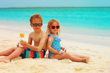 sun protection- happy little boy and girl with suncream at beach