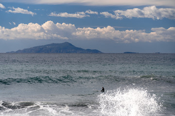 The surfer takes a wave, on a surfboard, slides along the wave, in the background of the mountain, Sorrento Italy
