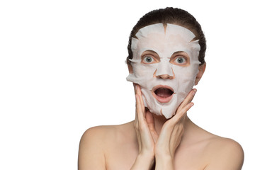 Beautiful young woman is applying a cosmetic mask on a face on a white background