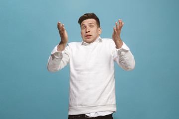 Fototapeta premium The young attractive man looking suprised isolated on blue