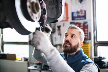 Man mechanic repairing a car in a garage.