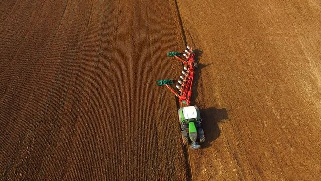 Tractor plowing a agricultural field - Tractor cultivating arable land for seeding crops, aerial view - 4K UHD
