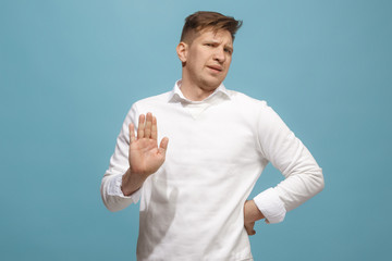 Fototapeta premium Young man with disgusted expression repulsing something, isolated on the blue