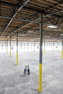 Owner of new warehouse and architect going over blueprint of new interior layout