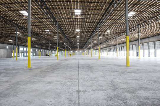 Wide angle interior view of large empty warehouse and loading dock doors