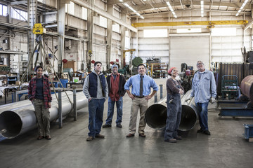Mixed race team of workers and Hispanic manager in a sheet metal factory.