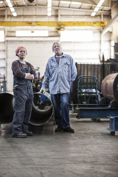 Black woman and Caucasian male workers in a sheet metal factory.
