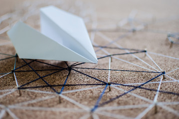 White paper plane over the threads linking the nails. Entities connected. Abstract concept (idea)...
