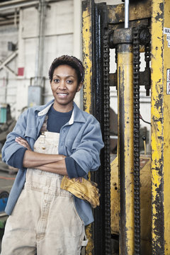 Black woman factory worker and a fork lift in a sheet metal factory.