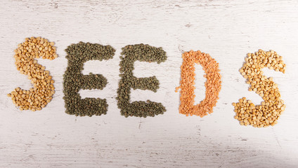 Seeds sign made with raw green and red lentil and peas on wooden textured background