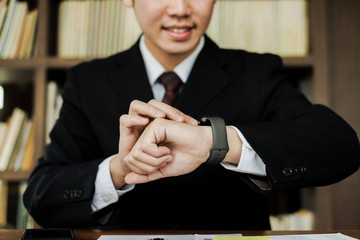 Young businessman look smart wrist watch in the office, business concept