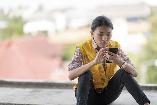 Lonely Woman In Yellow Vest Sitting Check Her Smartphone Alone On Lunch Break.