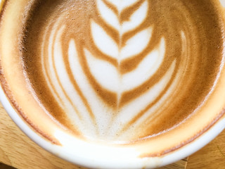 Hot latte coffee with art milk foam on wooden table