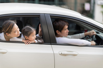 Happy man and woman with little child driving in car.Family safety transport road trip and happy people concept.