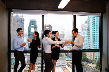 businessman and businesswoman are drinking champagne talking and smiling while celebrating in office, successful business concept.