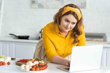 beautiful woman using laptop in kitchen