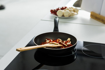 frying pan with delicious vegetables on electric stove in kitchen