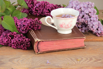 Bouquet of lilacs and an old album on a wooden table