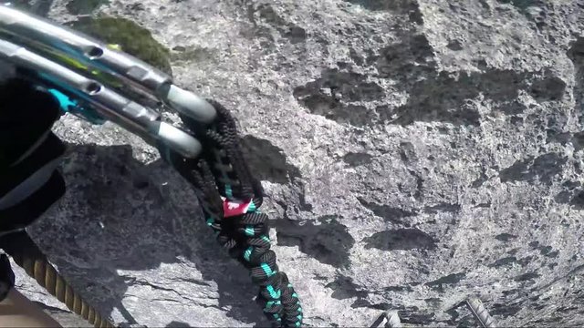 POV - a man climbs up a cliff with the help of iron handles